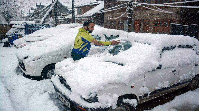 Srinagar: A man clears snow from his car during snowfall, in Srinagar, Monday, Jan. 30, 2023. (PTI Photo)(PTI01_30_2023_000021B)