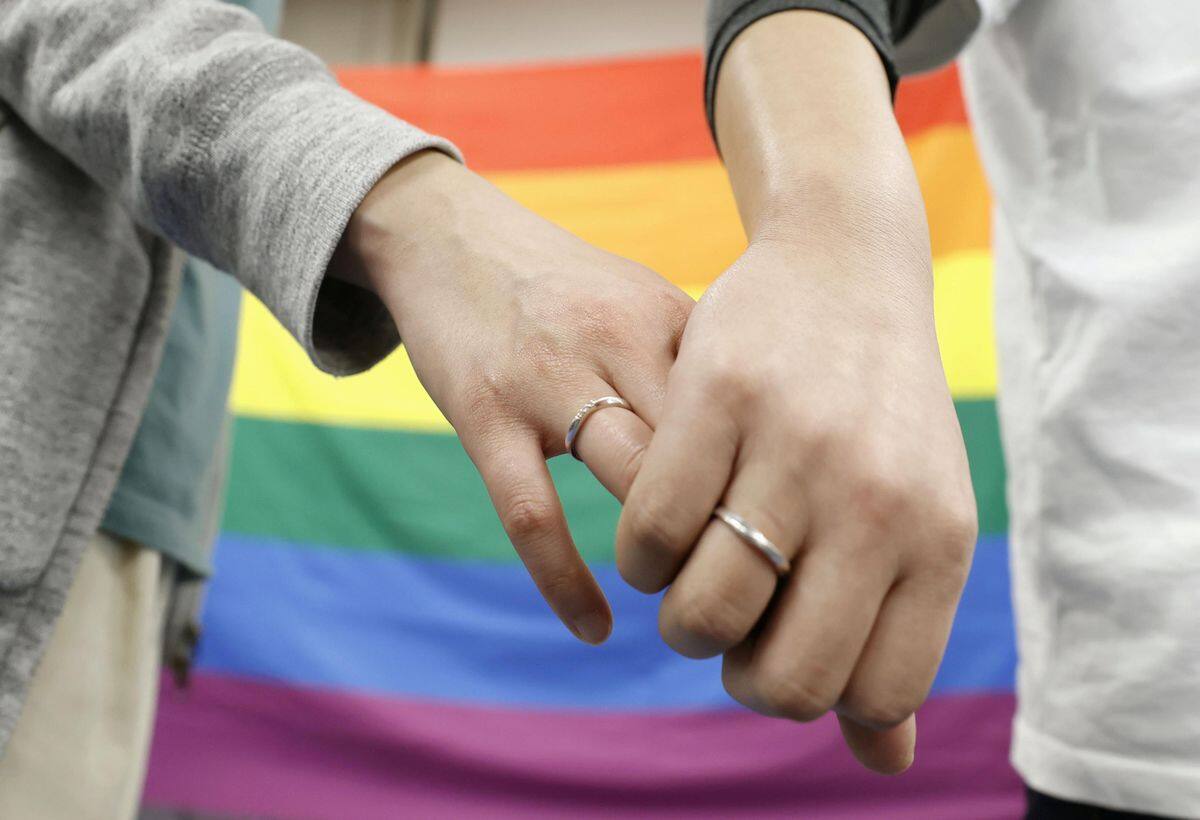 Plaintiffs hold hands each other after a district court ruled on the legality of same-sex marriages outside Sapporo district court in Sapporo