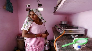 A housewife cooks on a stove using a Liquefied Petroleum Gas cylinder in her kitchen at Dujana village