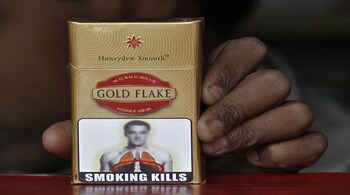 A vendor holds a cigarette pack printed with a picture bearing likeness to Chelsea's soccer player John Terry at his roadside stall in New Delhi January 3, 2012. A blurry picture of Terry appears on Gold Flake cigarette packets across the country with an anti-smoking warning was created by the Indian government's Directorate of Visual Publicity and got approved by the health ministry last year. The advertisement has triggered complaints from Terry's representatives, local media reported. REUTERS/Parivartan Sharma (INDIA - Tags: HEALTH SPORT SOCCER) - RTR2VU99