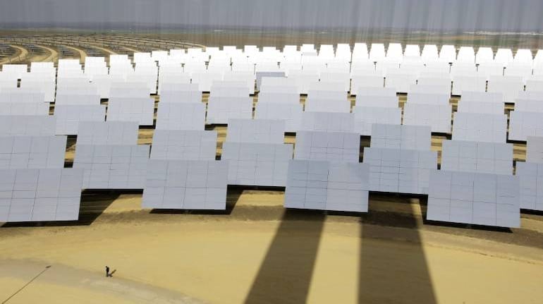 A man walks next to solar panels (bottom L) at a soon-to-be completed solucar solar park at Sanlucar La Mayor, near Seville, February 13, 2008. The first of two solar thermal power plants uses mirrors to concentrate the sun's rays onto the top of a 100 metre (300 foot) tower where it produces steam to drive a turbine. The lines in the photograph are due to reflections on the solar panels. REUTERS/Marcelo del Pozo (SPAIN) - RTR1X1BR