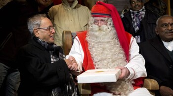 Indian President Pranab Mukherjee (L) receives a Christmas present from a person dressed as Santa Claus at the Santa Claus Village at the Arctic Circle near Rovaniemi October 16, 2014. REUTERS/Kaisa Siren/Lehtikuva (FINLAND - Tags: POLITICS TRAVEL)
ATTENTION EDITORS - THIS IMAGE WAS PROVIDED BY A THIRD PARTY. THIS PICTURE IS DISTRIBUTED EXACTLY AS RECEIVED BY REUTERS, AS A SERVICE TO CLIENTS. NO THIRD PARTY SALES. NOT FOR USE BY REUTERS THIRD PARTY DISTRIBUTORS. FINLAND OUT. NO COMMERCIAL OR EDITORIAL SALES IN FINLAND - RTR4AGGV