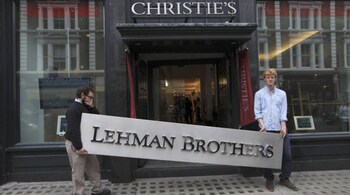 Christie's employees pose for a photograph with a Lehman Brothers sign at Christie's in central London September 24, 2010. Various items are on display before the auction of Lehman Brothers: Artwork and Ephemera, which will take place on September 29. REUTERS/Andrew Winning (BRITAIN - Tags: ENTERTAINMENT BUSINESS SOCIETY) - RTXSLK5