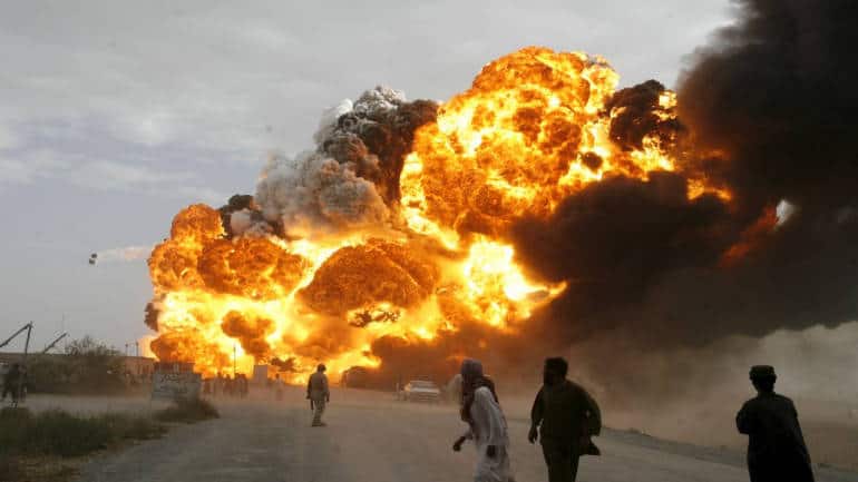 Men run away from burning oil tankers, used to carry fuel for NATO forces in Afghanistan, as they explode