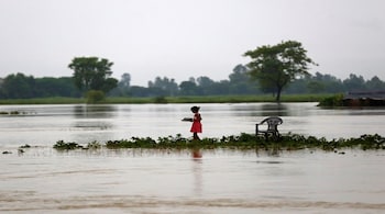 A girl carrying dishes walks along a flooded area in Janakpur, Nepal August 13, 2017. REUTERS/Navesh Chitrakar - RTS1BLUP