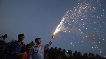A Hindu devotee holds a firework in his hand as he worships the Sun god during the Hindu religious festival "Chhat Puja" in Mumbai, November 19, 2012. Hindu devotees worship the Sun god and fast all day for the betterment of their family and society during the festival. REUTERS/Vivek Prakash (INDIA - Tags: RELIGION SOCIETY) - GM1E8BK036O01