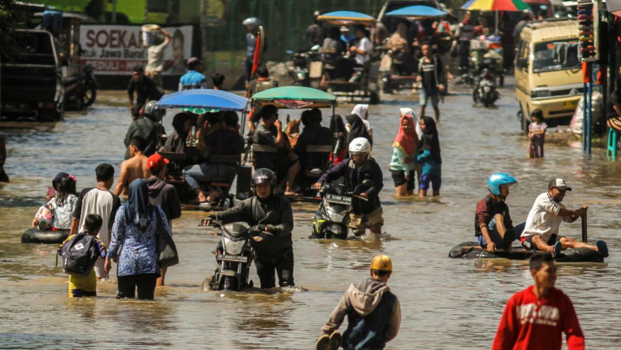 People wade through flood waters, caused by heavy seasonal rain, on a street in Bandung, West Java, Indonesia. (REUTERS)