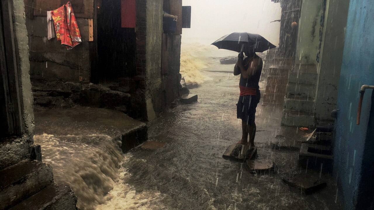 Mumbai: A man stand with an umbrella in a street amid heavy showers triggered by cyclone Ockhi in Mumbai on Tuesday. PTI Photo by Mitesh Bhuvad (PTI)
