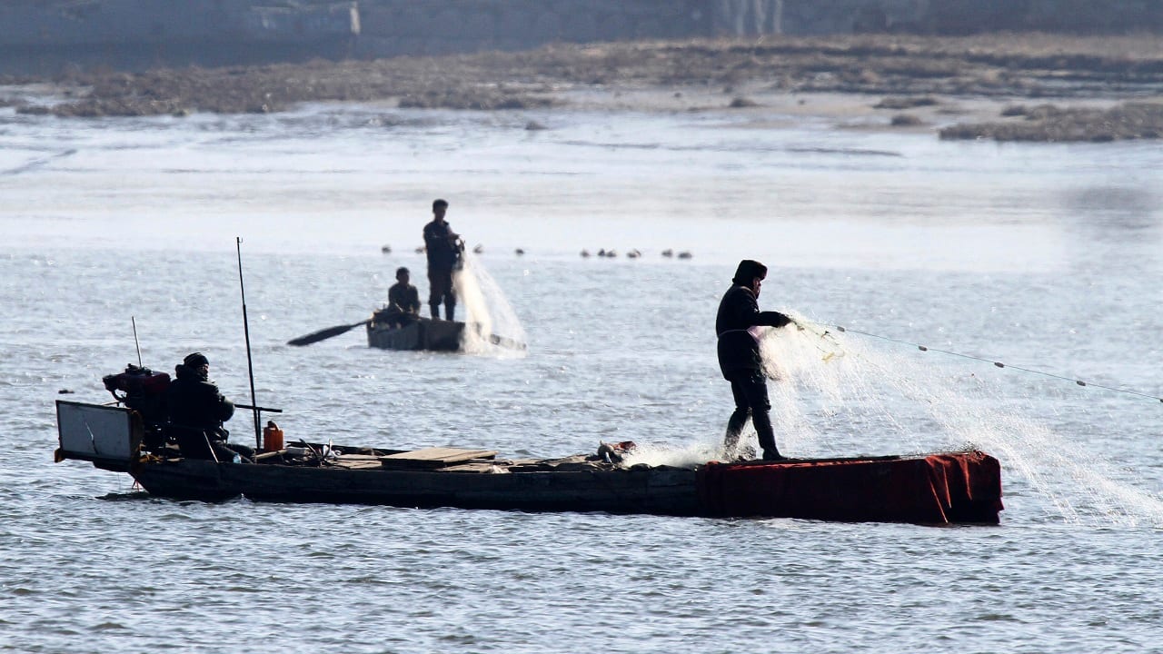 North Koreans fish on the Yalu River, near the North Korean town of Sinuiju, opposite the Chinese border city of Dandong, November 15, 2014. Picture taken November 15, 2014. REUTERS/Jacky Chen (CHINA - Tags: SOCIETY) - GM1EABG11KC01