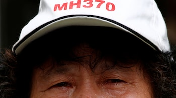 A family member of a passenger aboard Malaysia Airlines flight MH370 which went missing in 2014 reacts during a protest outside the Chinese foreign ministry in Beijing, July 29, 2016. The hat reads "Pray for MH370" REUTERS/Thomas Peter - S1BETSHOHBAA