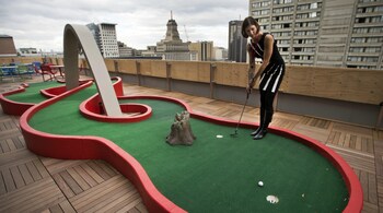 Google employee Andrea Janus demonstrates the use of the mini-putt green on the balcony at the Google office in Toronto. (Reuters)