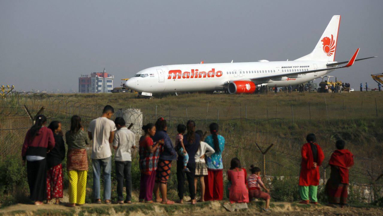 People watch a Malindo Air passenger plane after it skidded to the grassy area at the end of runway in Tribhuwan International Airport in Kathmandu, Nepal. (Image: AP/PTI)