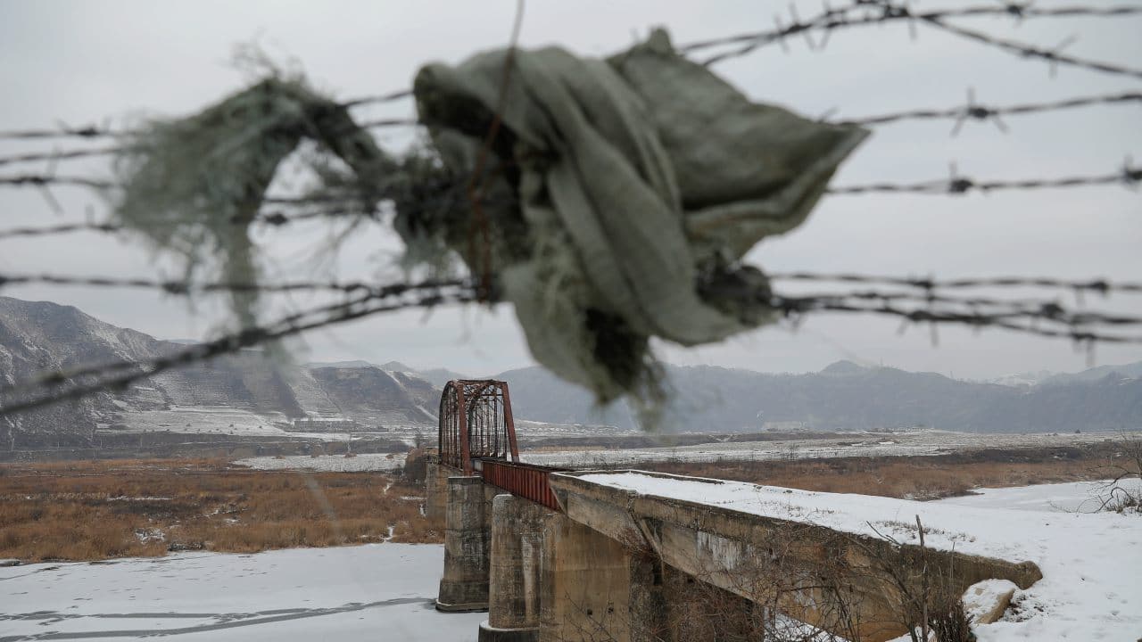 A piece of cloth is used to make a gap between a barbed-wire fence near the closed bridge over the Yalu River on the Chinese side of the border along North Korea between the towns of Ji'an and Linjiang in China. (Image: Reuters)