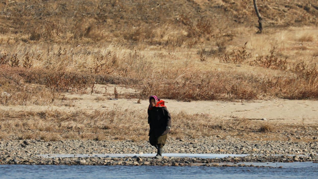 A North Korean woman is photographed from the Chinese side of the border north of Dandong, China as she walks on the banks of the Yalu River just north of Sinuiju, North Korea. (Image: Reuters)
