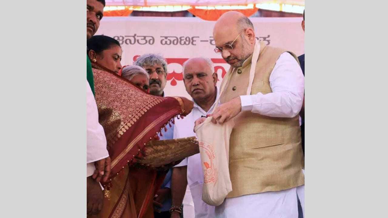 BJP chief Amit Shah collecting grains from farmers on the concluding day of “Musti Dhanya Sangraha Abhiyan” in Abbigeri Village, Gadag district of Karnataka on 12th April 2018. (PTI Photo) BJP chief Amit Shah collecting grains from farmers on the concluding day of “Musti Dhanya Sangraha Abhiyan” in Abbigeri Village, Gadag district of Karnataka on 12th April 2018. (PTI Photo)