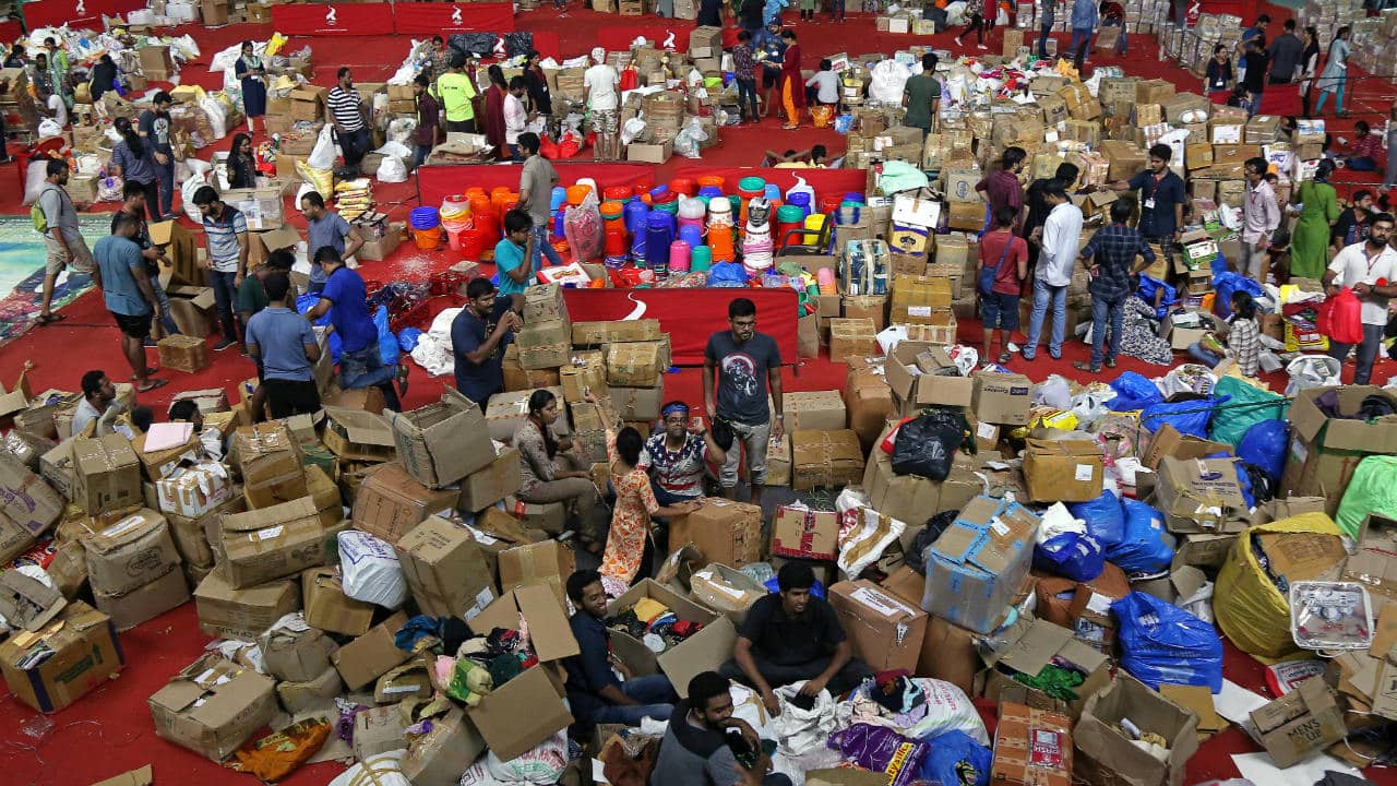 Prime Minister Narendra Modi has announced a grant of Rs 500 crore, besides the Rs 100 crore declared by Home Minister Rajnath Singh earlier. CM Vijayan is personally donating Rs 1 lakh to the Chief Minister’s Distress Relief Fund. Various states, corporate companies, businessmen and celebrities have also made donations in cash and kind. Pictured: Volunteers work at an aid distribution centre inside a stadium in Kochi. (Image: Reuters)