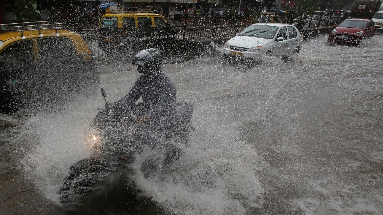 Man speeds through a waterlogged street as most of the city's roads remain overrun with water during the ongoing monsoon rains. (Image: AP)