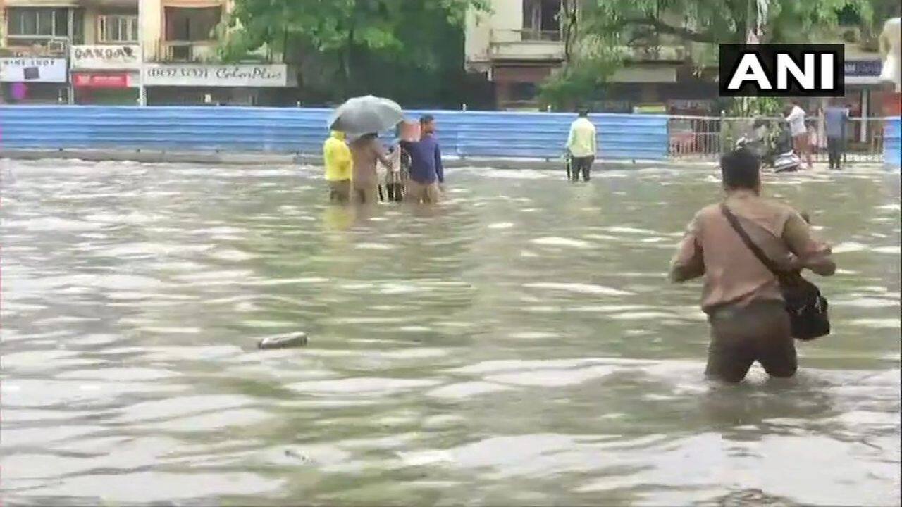 Streets in the city flooded due to heavy rainfall, people wade through water in Gandhi Market area, Sion. (Image: ANI)