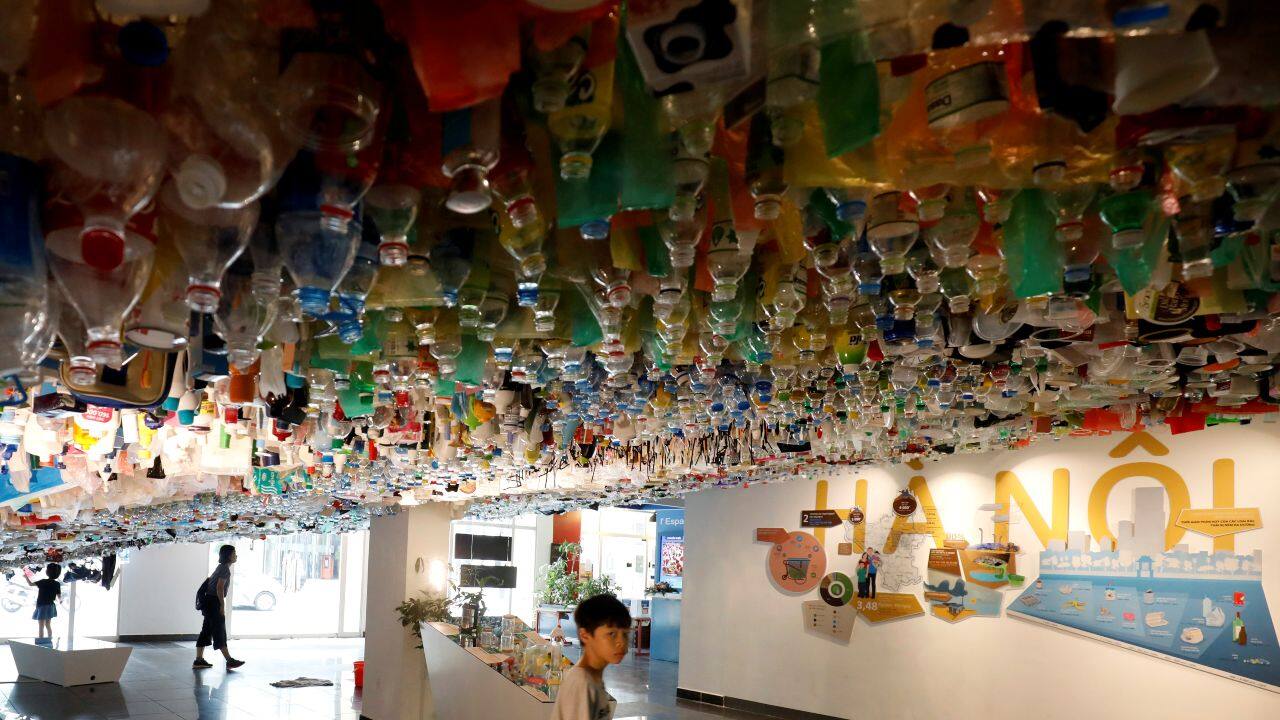 Members of a family visit a hanging art installation made from scraps of plastic bags, bottles, cans and containers at an exhibition entitled Reduce, at the French Cultural Center in Hanoi, Vietnam. (Image: Reuters)