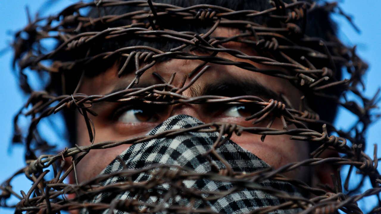A masked Kashmiri man with his head covered with barbed wire attends a protest after Friday prayers during restrictions following the scrapping of the special constitutional status for Kashmir by the Indian government, in Srinagar on October 11, 2019. (Image: Reuters/Danish Ismail)
