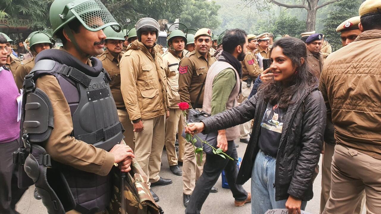 A demonstrator is seen giving a rose flower to a security personnel at Jantar Mantar. People had gathered there to protest against the CAA. (Image: Twitter)