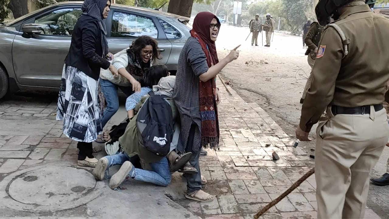 Women form a human shield around a man being beaten by police officers during protests against amended Citizenship Act, at Jamia Millia Islamia University in New Delhi on December 15, 2019 in this screen grab obtained from a social media video. (Image: Ghulam Hussain/via Reuters)