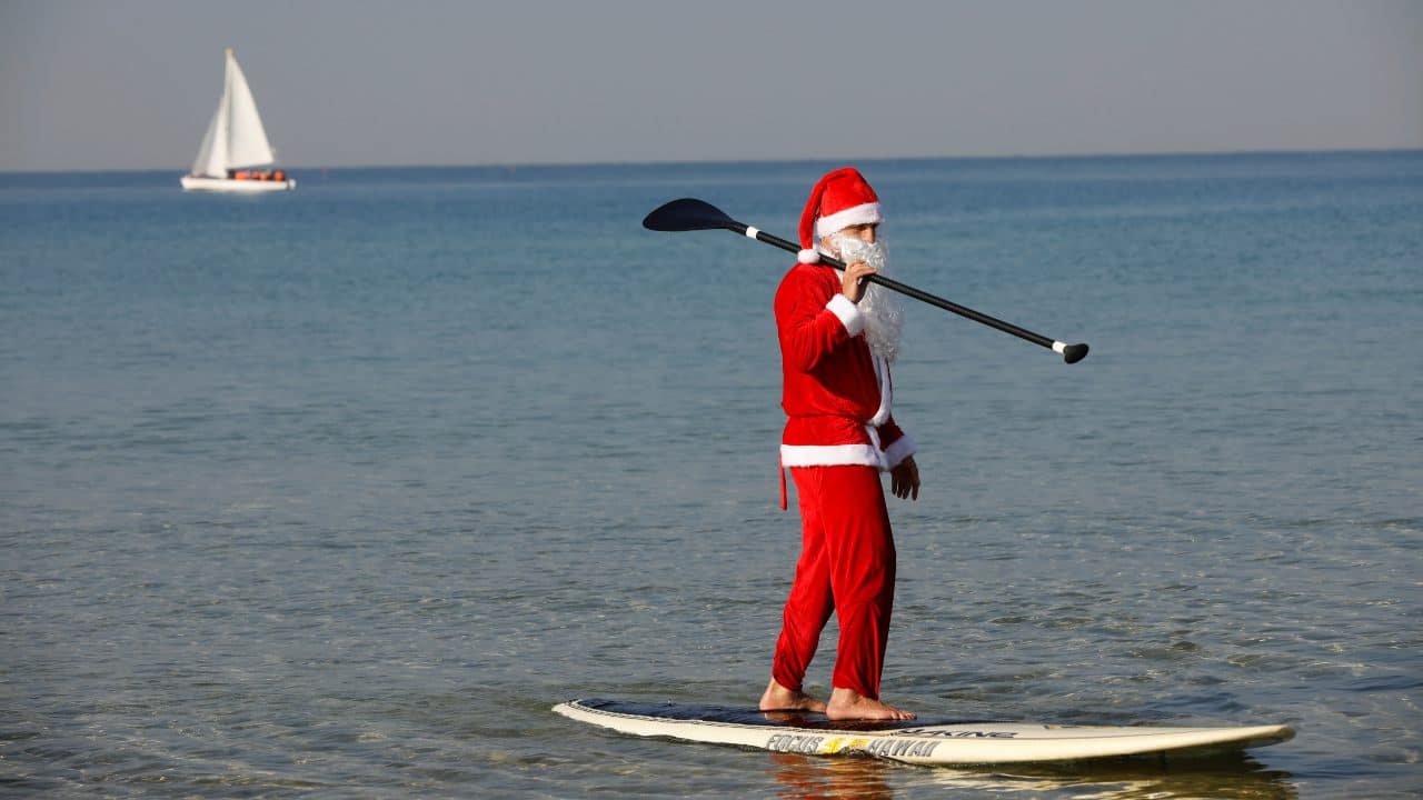 A man wearing a Santa Claus costume paddles on a SUP board in the Mediterranean Sea during an event organised by the Tel Aviv municipality, off the coast of Tel Aviv, Israel (Image: Reuters)