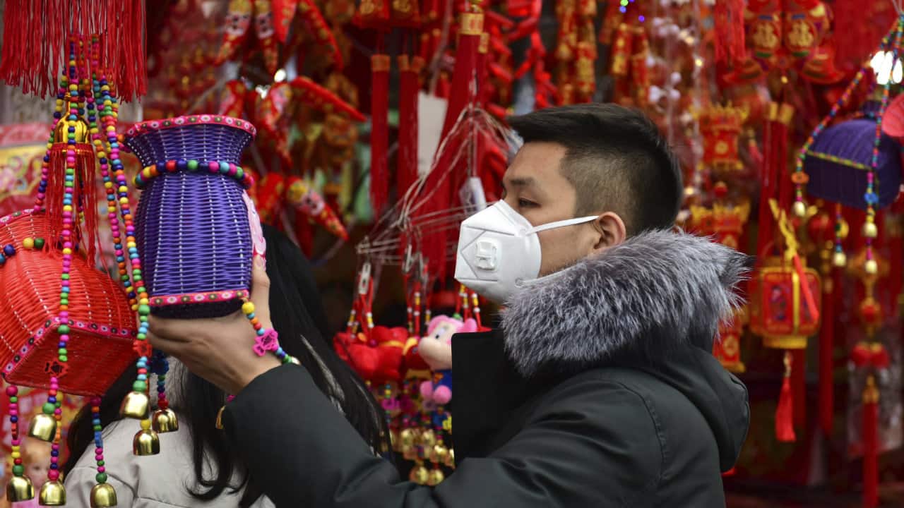 A man wears a face mask as he shops for decorations for the upcoming Lunar New Year, the Year of the Rat, at a market in Fuyang in central China's Anhui Province. China closed off a city of more than 11 million people Thursday in an unprecedented effort to try to contain a deadly new viral illness that has sickened hundreds and spread to other cities and countries in the Lunar New Year travel rush. (Image: Associated Press)