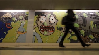 A woman walks past murals adorning the walls of Garibaldi subway station, in Milan, Feb. 28, 2020. (AP Photo/Luca Bruno)
