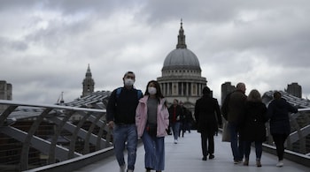People wearing face masks walk across the Millennium footbridge backdropped by the dome of St Paul's Cathedral in London, Tuesday, March 10, 2020. Starkly illustrating the global east-to-west spread of the new coronavirus, Italy began an extraordinary, sweeping nationwide travel ban on Tuesday while in China, the diminishing threat prompted the president to visit the epicenter and declare: ""We will certainly defeat this epidemic." (AP Photo/Matt Dunham)