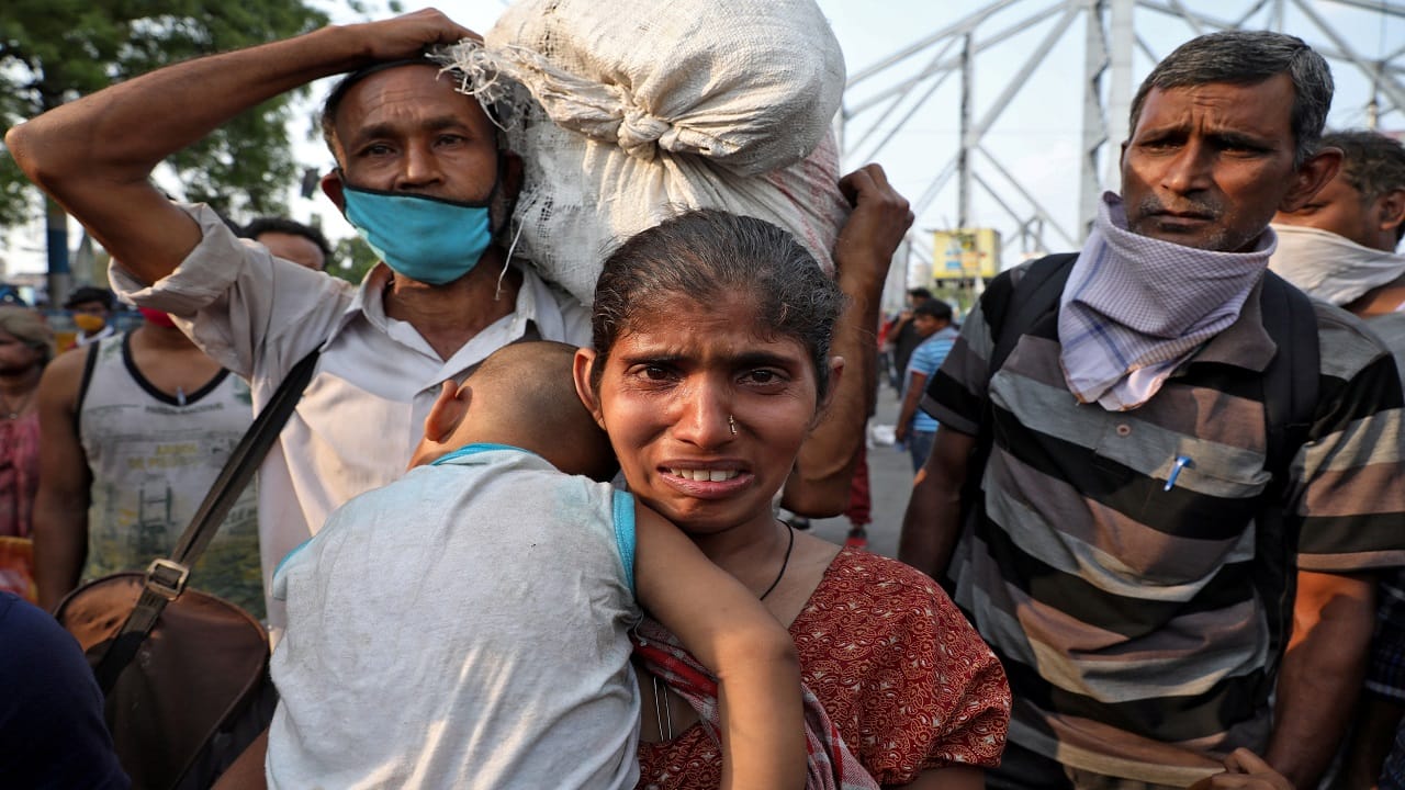 A migrant worker holding her baby cries after she missed out on receiving free food outside Howrah railway station, Kolkata, March 25. REUTERS