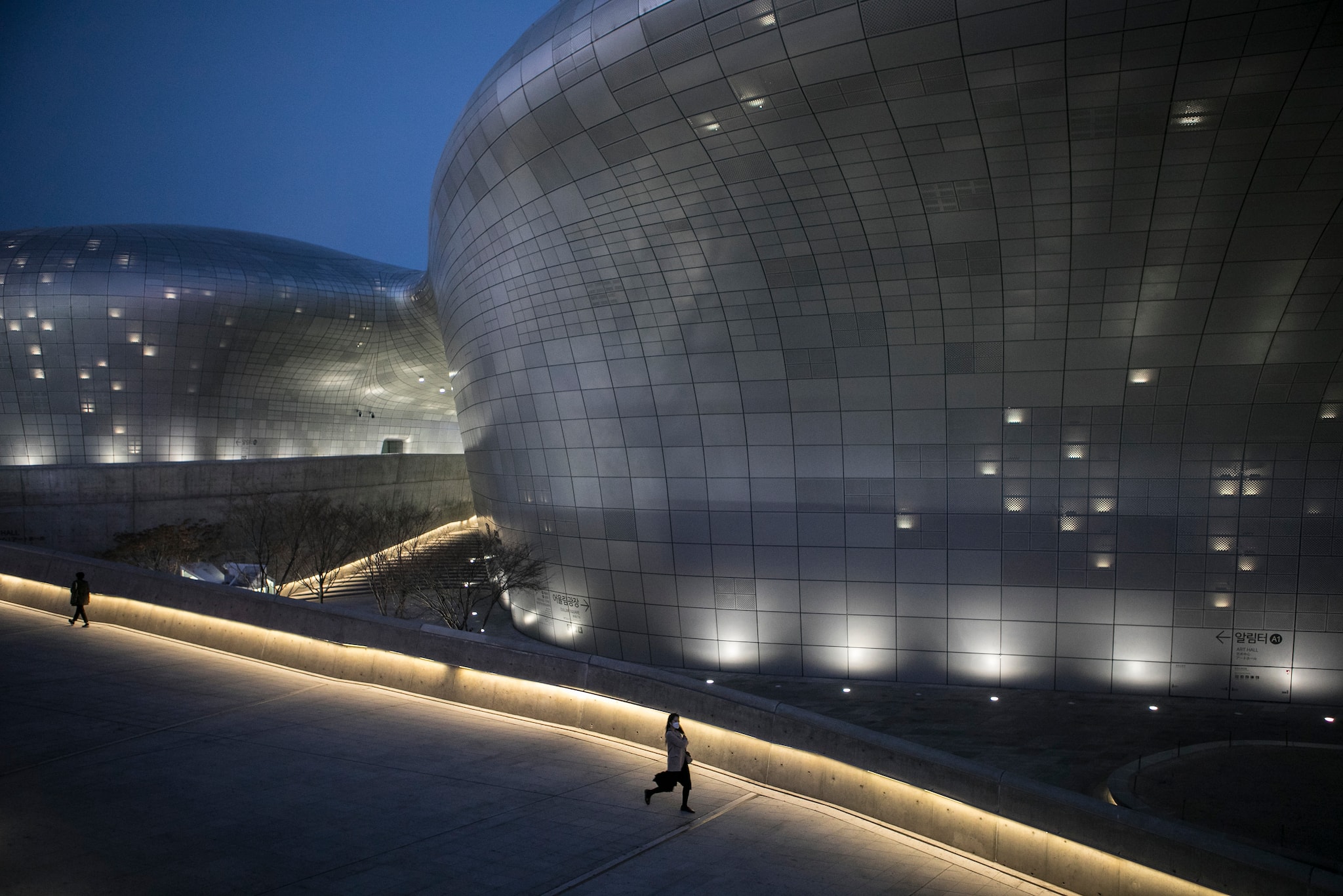 People walk through Dongdaemun Design Plaza in the city center of Seoul, South Korea on March 20, 2020. (Woohae Cho/The New York Times)