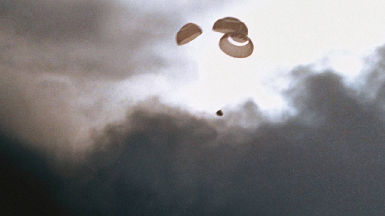In this April 17, 1970 photo made available by NASA, the command module carrying the Apollo 13 crew parachutes to a splashdown in the Pacific Ocean. (NASA via AP)