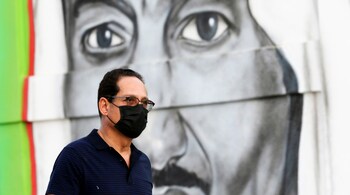 A Saudi man walks past a poster depicting Saudi King Salman bin Abdulaziz, after a curfew was imposed to prevent the spread of the coronavirus disease (COVID-19), in Riyadh (REUTERS/Ahmed Yosri)