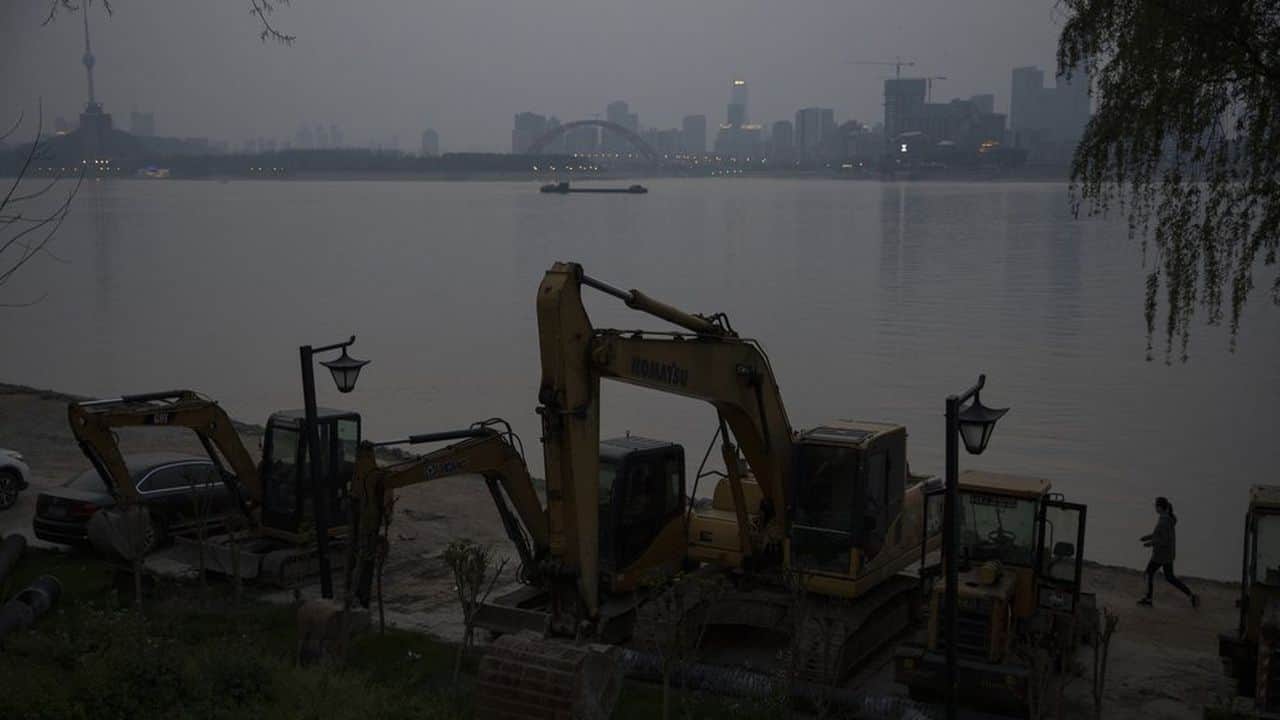 A resident wearing a mask against the new coronavirus walks past idling digging machineries along the Yangtze River in Wuhan in central China's Hubei province. (AP)