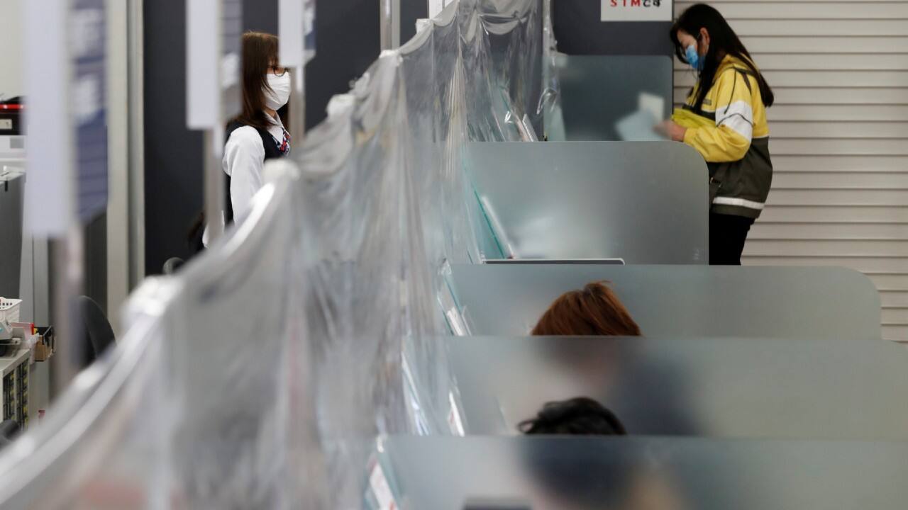 A bank teller wearing a protective face mask stands at a counter with a plastic curtain installed to prevent the spread of coronavirus, at the Higashinakano branch of MUFG Bank in Tokyo, Japan, on April 24. A bank teller wearing a protective face mask stands at a counter with a plastic curtain installed to prevent the spread of coronavirus, at the Higashinakano branch of MUFG Bank in Tokyo, Japan, on April 24.