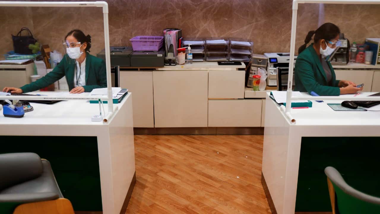People wear protective face shields and masks at a bank getting ready to reopen in Bangkok, Thailand, on May 14. (Image: Reuters) People wear protective face shields and masks at a bank getting ready to reopen in Bangkok, Thailand, on May 14. (Image: Reuters)