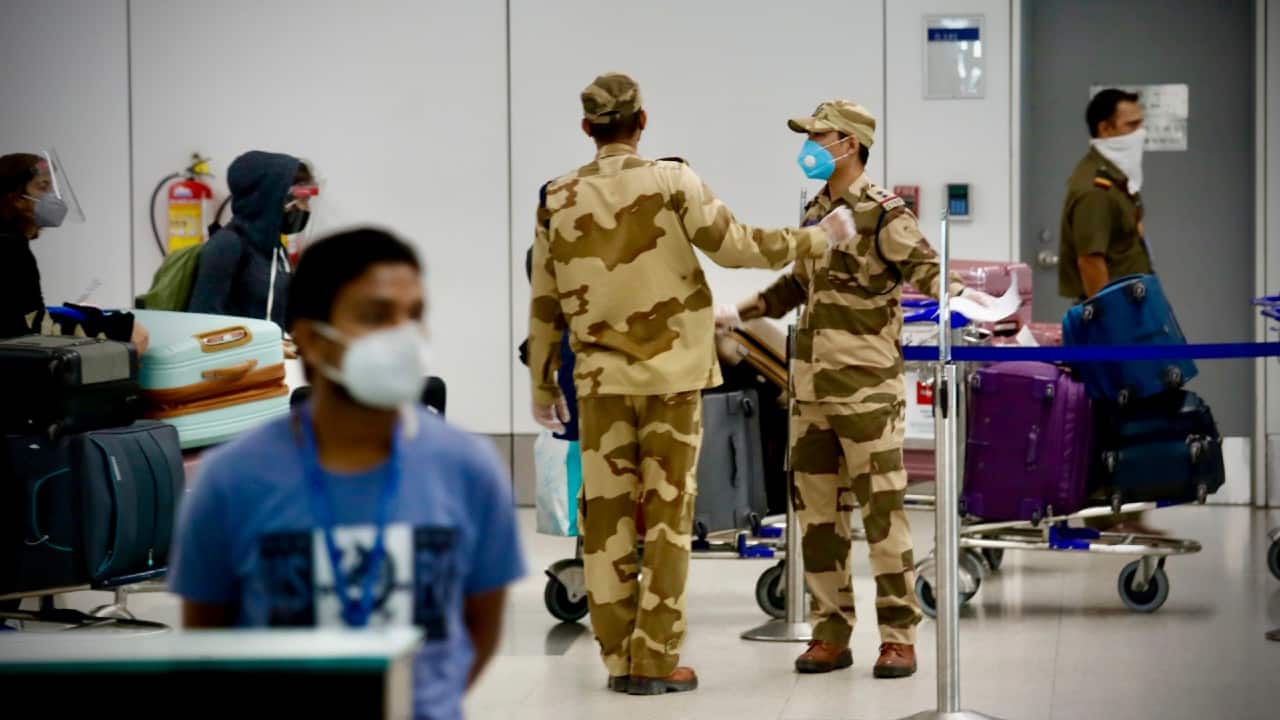 Security officers stand guard as Indians stranded in Singapore arrive at the Indira Gandhi International airport in New Delhi on May 8. (Image: AP)