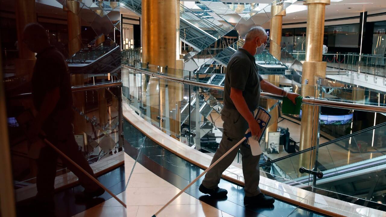 A worker wearing a face mask to protect against coronavirus cleans inside a mall during its reopening in Athens. (Image: AP)