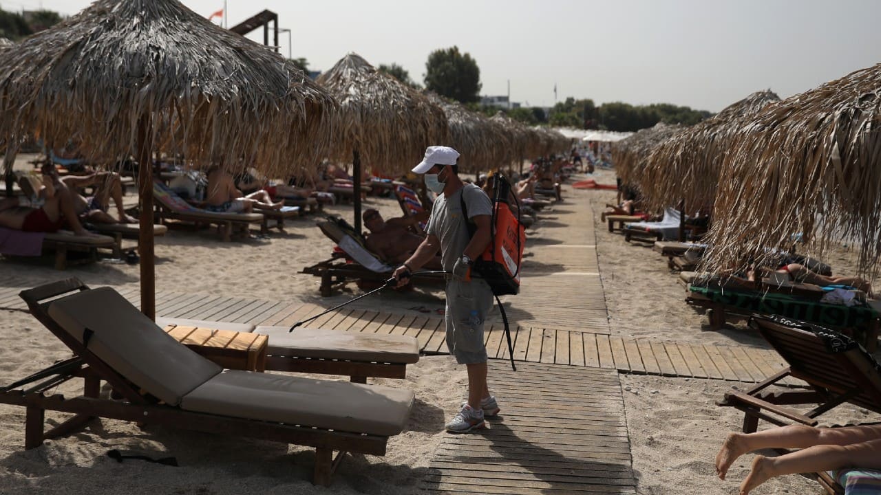 A man wearing a face mask disinfects a sunbed during the official reopening of beaches to the public following the easing of measures against the spread of coronavirus in Athens. (Image: Reuters)