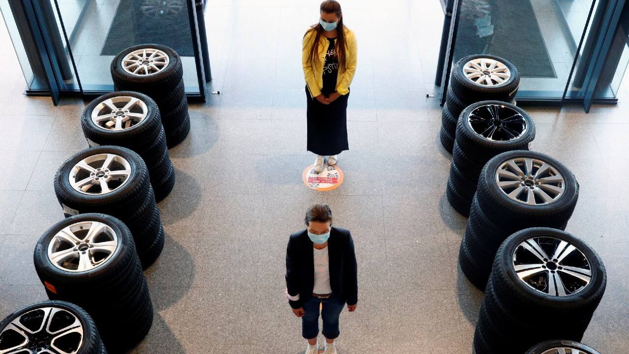 People stand on social-distancing markers at a Mercedes car dealer in Brussels, Belgium, on May 6. (Image: Reuters) People stand on social-distancing markers at a Mercedes car dealer in Brussels, Belgium, on May 6. (Image: Reuters)