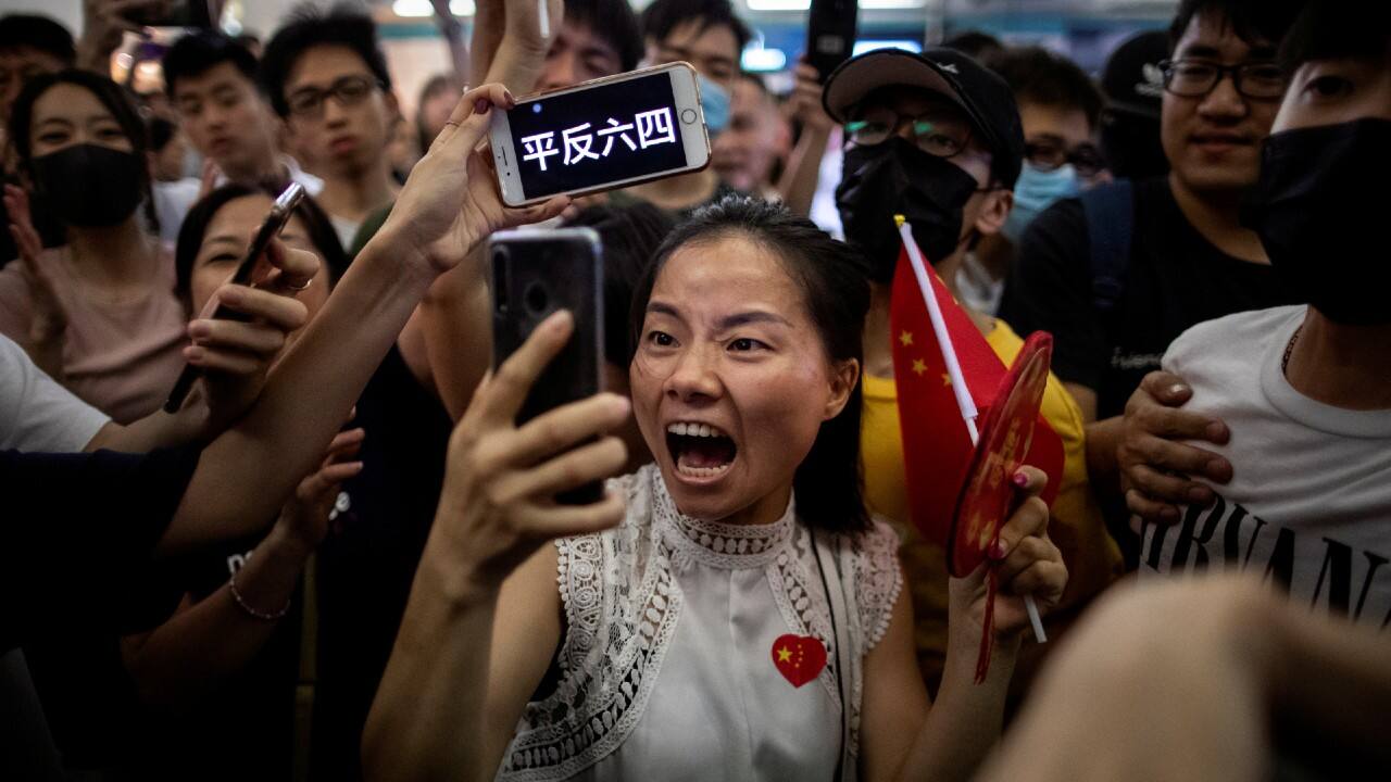 A pro-China demonstrator films herself as an anti-government protester holds up a sign on her phone during skirmishes between the two opposing groups at Yuen Long station in Hong Kong, China, September 12, 2019. The words on the phone read, &quot;Seek an official reassessment of the June 4 crackdown,&quot; referring to the 1989 Tiananmen Square protests. (Image: Reuters /Jorge Silva)