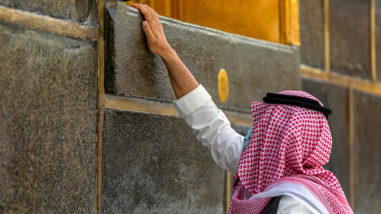 A pilgrim touches the Kaaba, the square structure in the Great Mosque, toward which believers turn when praying, in Mecca, Saudi Arabia, July 27. (Saudi Ministry of Media via AP)