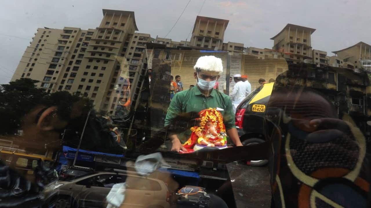 A devotee wearing a mask carries home an idol of elephant-headed Hindu god Ganesha for worship during Ganesh Chaturthi festival celebrations in Mumbai, India, Saturday, Aug. 22, 2020. The 10-day long Ganesh festival began Thursday and ends with the immersion of Ganesha idols in water bodies on the final day. (Image: AP Photo/Rafiq Maqbool)