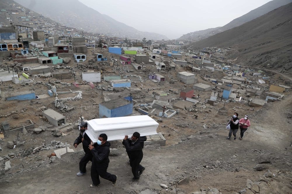 Cemetery workers carry the coffin that contains the remains of Wilson Gil, who died of COVID-19 related complications, to a burial site at the Martires 19 de Julio cemetery on the outskirts of Lima, Peru on August 26. (Image: AP Photo/Martin Mejia)