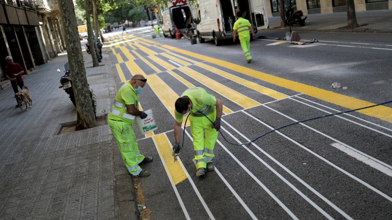 Worker paint lines on the street to expand a sidewalk for pedestrians to keep a social distance between them in Barcelona, Spain, May 5. (Image: Reuters)