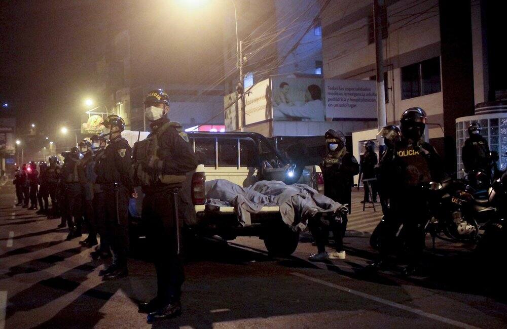 Police officers stand guard near two bodies outside a disco in Lima, Peru on August 23, following a fatal stampede. (Image: AP Photo/Diego Vertiz)