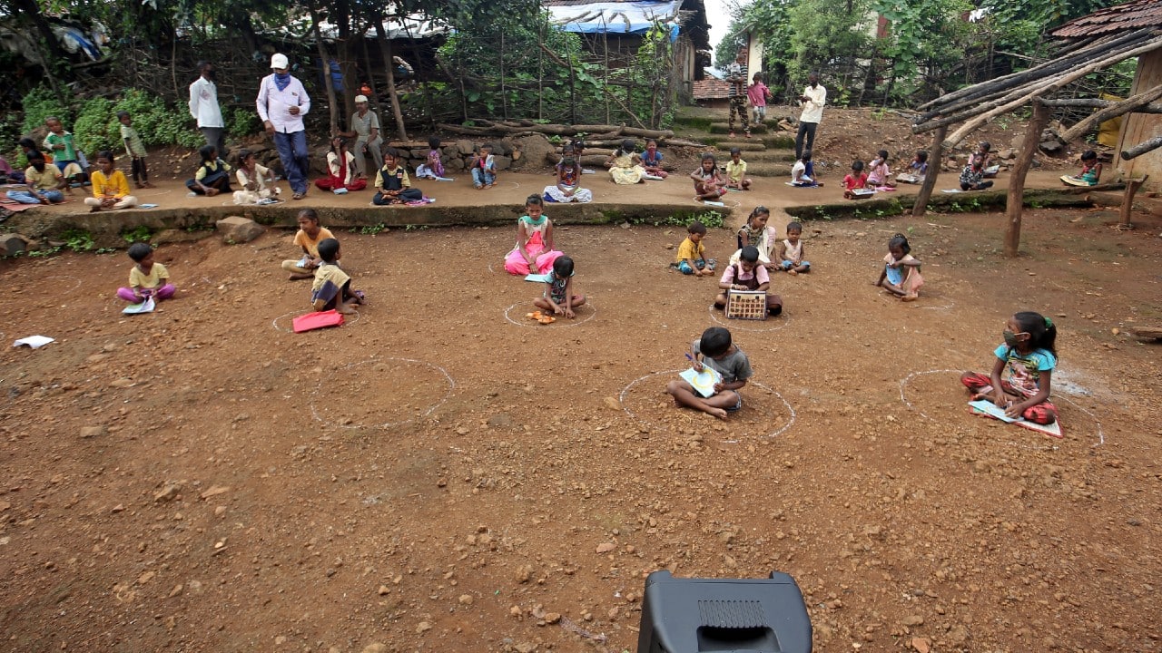 Children, who have missed their online classes due to a lack of internet facilities, maintain a safe distance as they listen to pre-recorded lessons over loudspeakers, after schools were closed following the COVID-19 pandemic in Dandwal village in the western state of Maharashtra, India, July 28. (Image: Reuters)