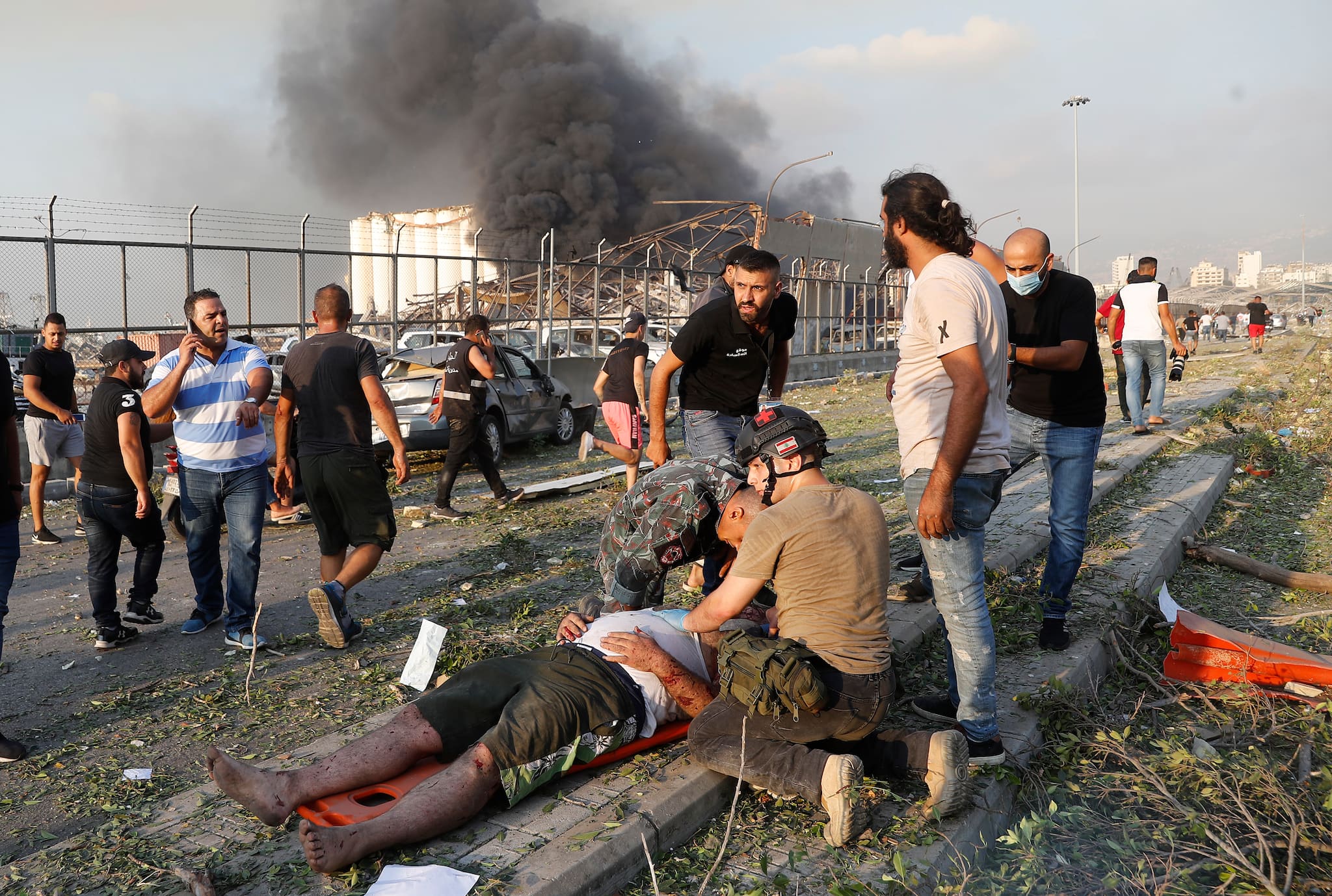 Rescue workers help an injured man at the explosion scene that hit the seaport of Beirut, Lebanon, Tuesday, Aug. 4, 2020. (AP Photo/Hussein Malla)