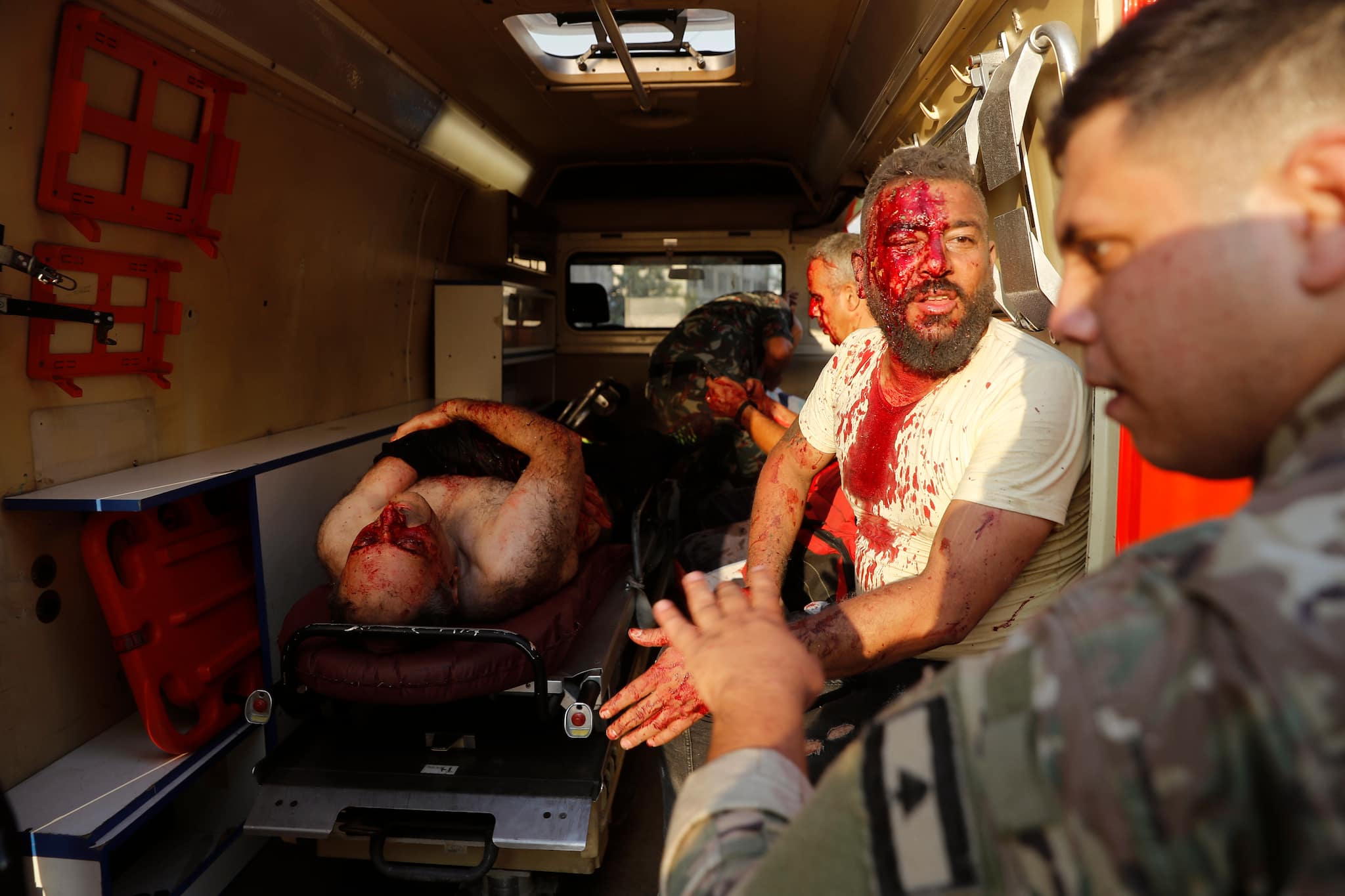 A Lebanese soldier, right, checks on injured men who sit inside an ambulance at the explosion scene that hit the seaport of Beirut, Lebanon, Tuesday, Aug. 4, 2020. (AP Photo/Hussein Malla)